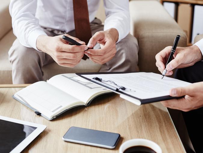 Businessman pointing at contract while showing his partner where to sign it